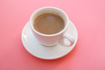 Cup of coffee on pink background.