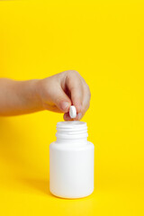 pharmacy colorful medicament pills on child (toddler) hands on yellow background