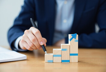 Close-up of a person's hand pointing at a wooden block chart representing business growth.