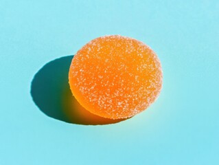 Round sugary orange candy on bright blue background capturing sweetness and texture