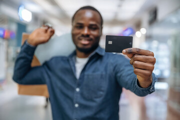 Credit card for shopping. Black man is in the hall of the supermarket
