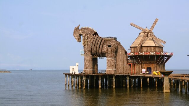 Giant statues of Trojan horses and windmills at mangrove beach made of wood, at Bee Jay Bakau Resort BJBR, landmark of Probolinggo, East Java, Indonesia, wooden craft art