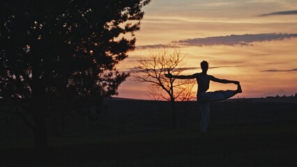 A mesmerizing sunset silhouette captures a graceful dancer in a serene natural landscape