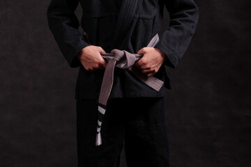 gray-white belt with progressive stripes on a black kimono for Brazilian jiu-jitsu