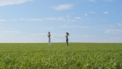Two happy individuals enjoying each others company in a lush green field under a clear blue sky