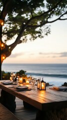 Summer travel experience with sustainable eco retreat. An elegant outdoor dining setup by the beach at sunset, featuring candles, decor, and a serene ocean view.