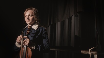 Fototapeta premium A Young Musician Intensely Preparing to Perform on Stage with a Beautiful Violin in Hand