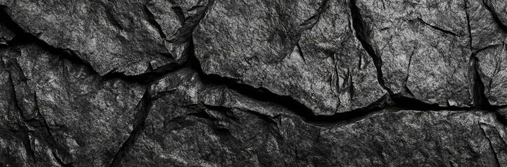 Black rock texture. Rough mountain surface with cracks. Close-up. Granite stone background with space for design. Web banner. Wide. Panoramic.