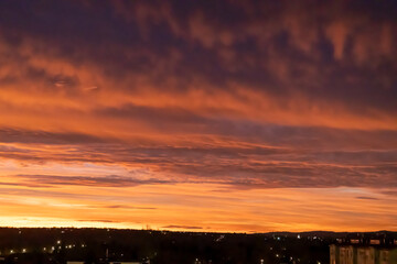 Sunrise sky with pink and orange clouds, silhouetted city skyline.