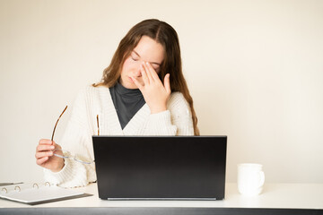 Tired overload young woman suffering from eye strain feeling headache working on a laptop at home office. Unhealthy student girl having dry eyes syndrome. The impact of screens on vision digital era