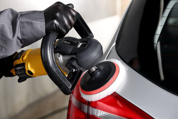 Obraz premium Man polishing car with orbital polisher indoors, closeup