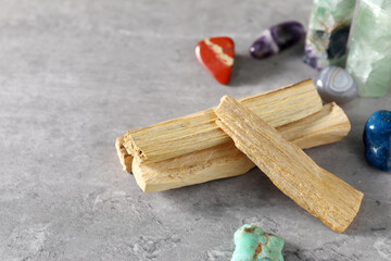 Palo santo sticks and gemstones on grey table, closeup. Space for text