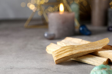 Palo santo sticks, gemstones and burning candles on grey table, closeup. Space for text