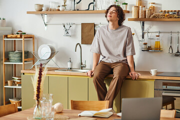 Young handsome man relaxing in a stylish office space filled with natural light and greenery