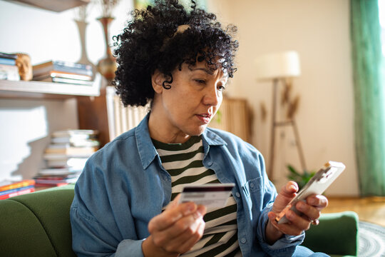 Woman shopping online with credit card and smartphone at home