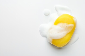 Soap bar with foam on white background, top view. Space for text