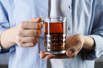 Woman with glass of tea in metal holder, closeup