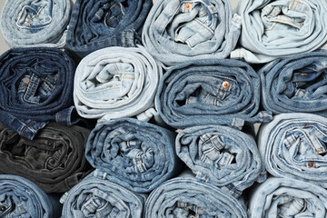 Different stylish rolled jeans as background, top view