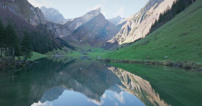 Drone, The calm waters of Lake Seealpsee in the Appenzell region of Switzerland reflect the surrounding mountains, creating a fascinating view. Sky, peaks and nature seem to meet on a single plane.