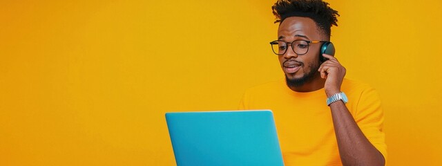 Young Man in Glasses Using Laptop While Talking on Headset
