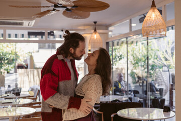 Couple enjoys a warm moment together in a cozy cafe with natural light