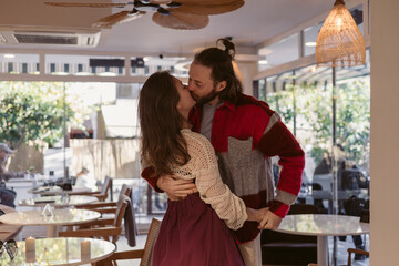 Couple shares an intimate moment in a cozy cafe during a sunny afternoon