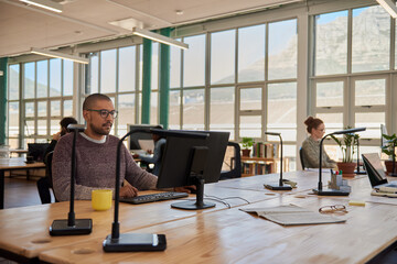 Young businessman and colleagues working in a large open plan office