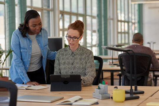Two diverse businesswomen working on a tablet together in an office