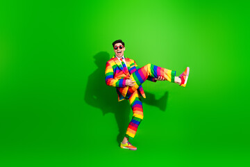 Vibrant Young Man in Rainbow Suit Enjoying a Fun and Colorful Moment on a Bright Green Background Capturing Joy and Style