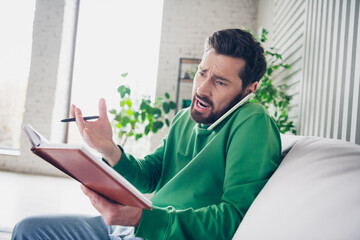 Casual young man multitasking with a phone call and notebook in a cozy home setting