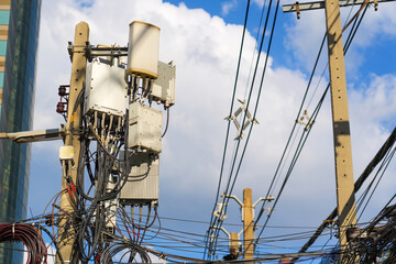 Utility poles rise into the sky, supporting numerous power lines and communication devices in a...
