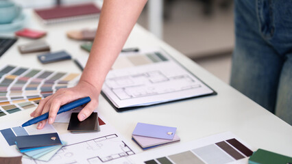 Design Decisions: An interior designer meticulously reviews blueprints, color swatches, and...