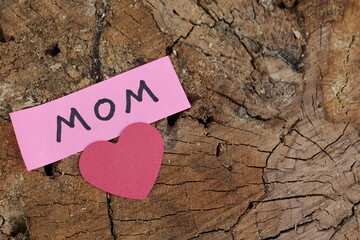 Una toma de cerca de la palabra madre acompañada de un corazón y lazo rojo  para ser utilizado el...