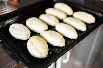 Molded raw pies on a baking sheet before baking. Homemade pies with meat, cherries, apples.