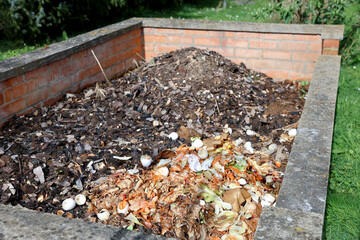 Large brick-built compost heap in various stages