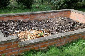 Large brick-built compost heap in various stages