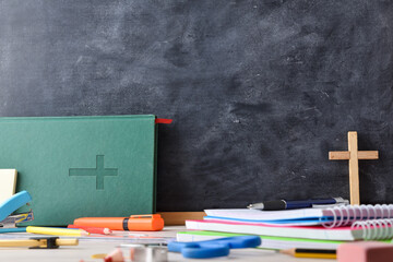 Educational background with blackboard, Bible and school supplies on desk