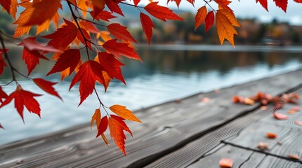 An autumn scene with vibrant orange and red leaves on tree branches framing a calm lake, a rustic wooden deck or table in the foreground, and blurred autumn foliage reflecting in the water