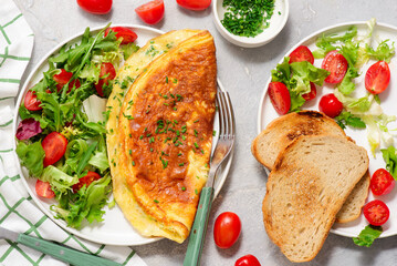 Cheese omelette with fresh green salad and toast on a plate