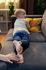 Mother tickling son's feet on sofa: playful family moments at home