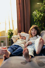 Obraz premium Mother tickling feet of daughter and son relaxing on sofa