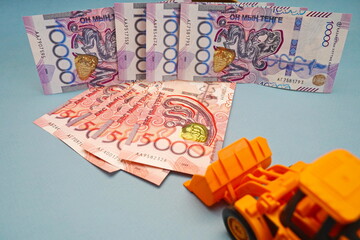Banknotes of Kazakhstani tenge 5000 and 10,000 and an excavator. Financing of construction and...