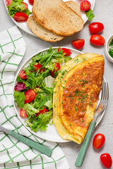 Cheese omelette with fresh green salad and toast on a plate