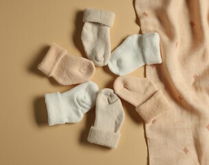 Baby blanket and socks on beige background, flat lay