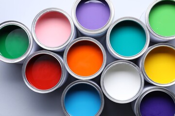 Cans of bright paints on grey background, flat lay