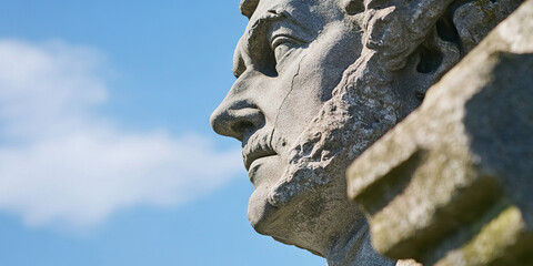 Obraz premium Profile View of Weathered Stone Bust Against Sky