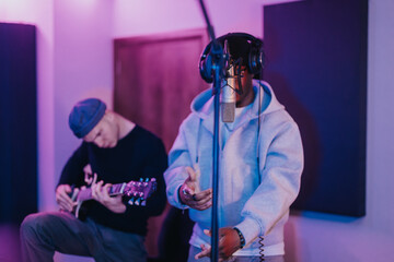 Singer and guitarist collaborate in a recording studio, showcasing a creative musical process. The...