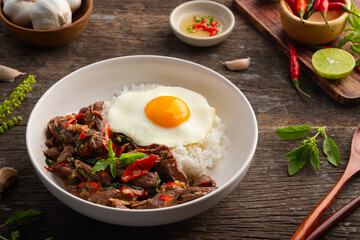 Stir fried sliced Beef with Holy Basil and Cooked Rice topped with fried egg in black plate.Thai spicy food(Pad Kra pao)