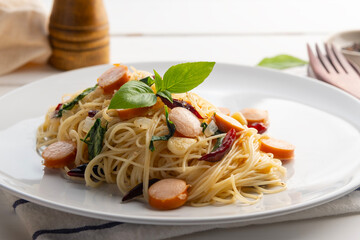 Close up Stir Fried angel hair pasta With Dried Chili garlic and sliced sausage in white plate.