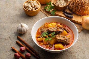 Massaman Curry with beef.Cooked beef meat and potatoes groundnut with massaman curry paste in coconut milk on white bowl.asian food.
